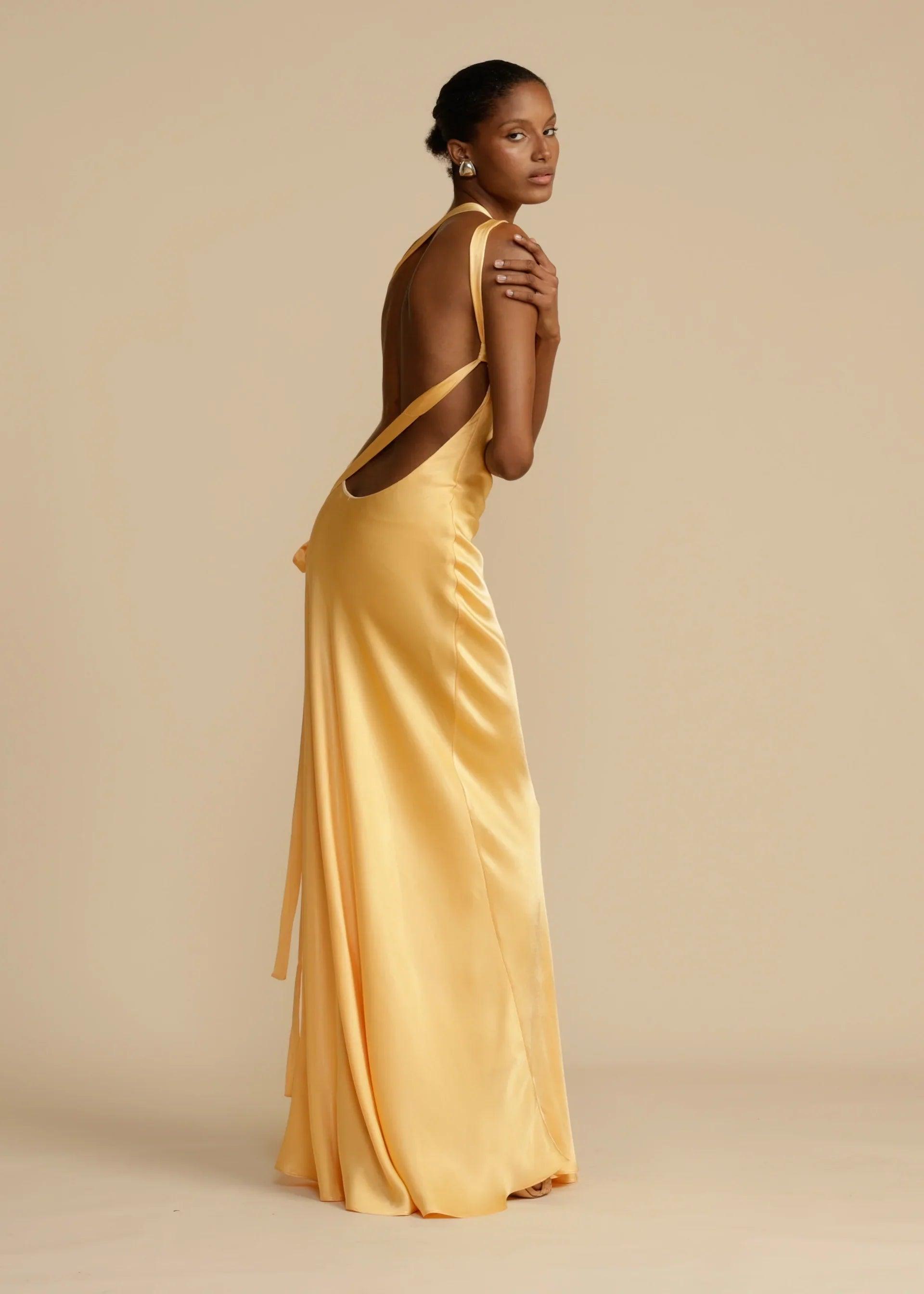 Vestido Longo Aurelia em satin jacquard amarelo com decote assimétrico e costas abertas, ideal para eventos sofisticados. Majestique.6