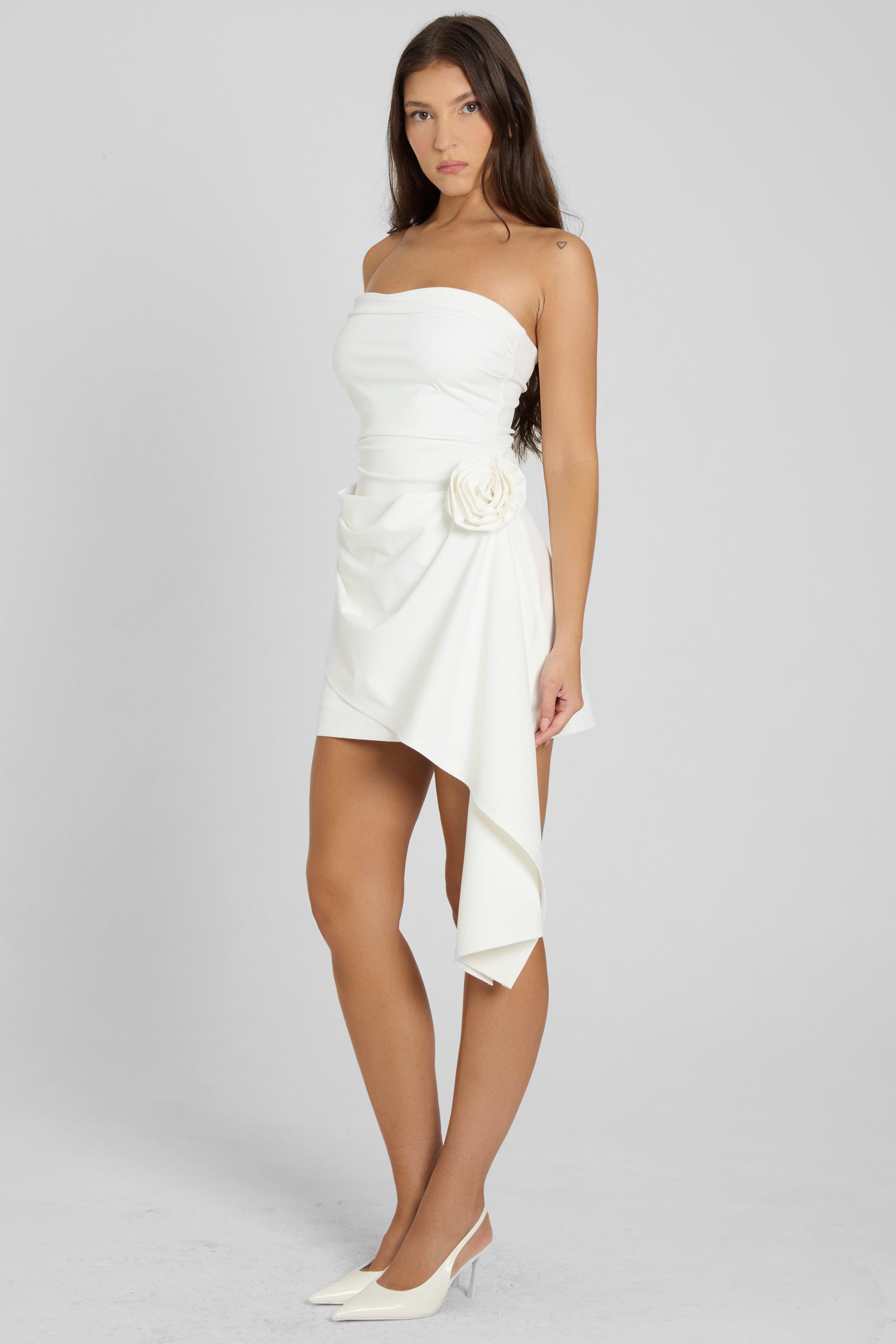 Vestido Mini Fleur em branco com decote tomara que caia, saia assimétrica com babados e roseta aplicada, ideal para eventos sofisticados. Majestique.6